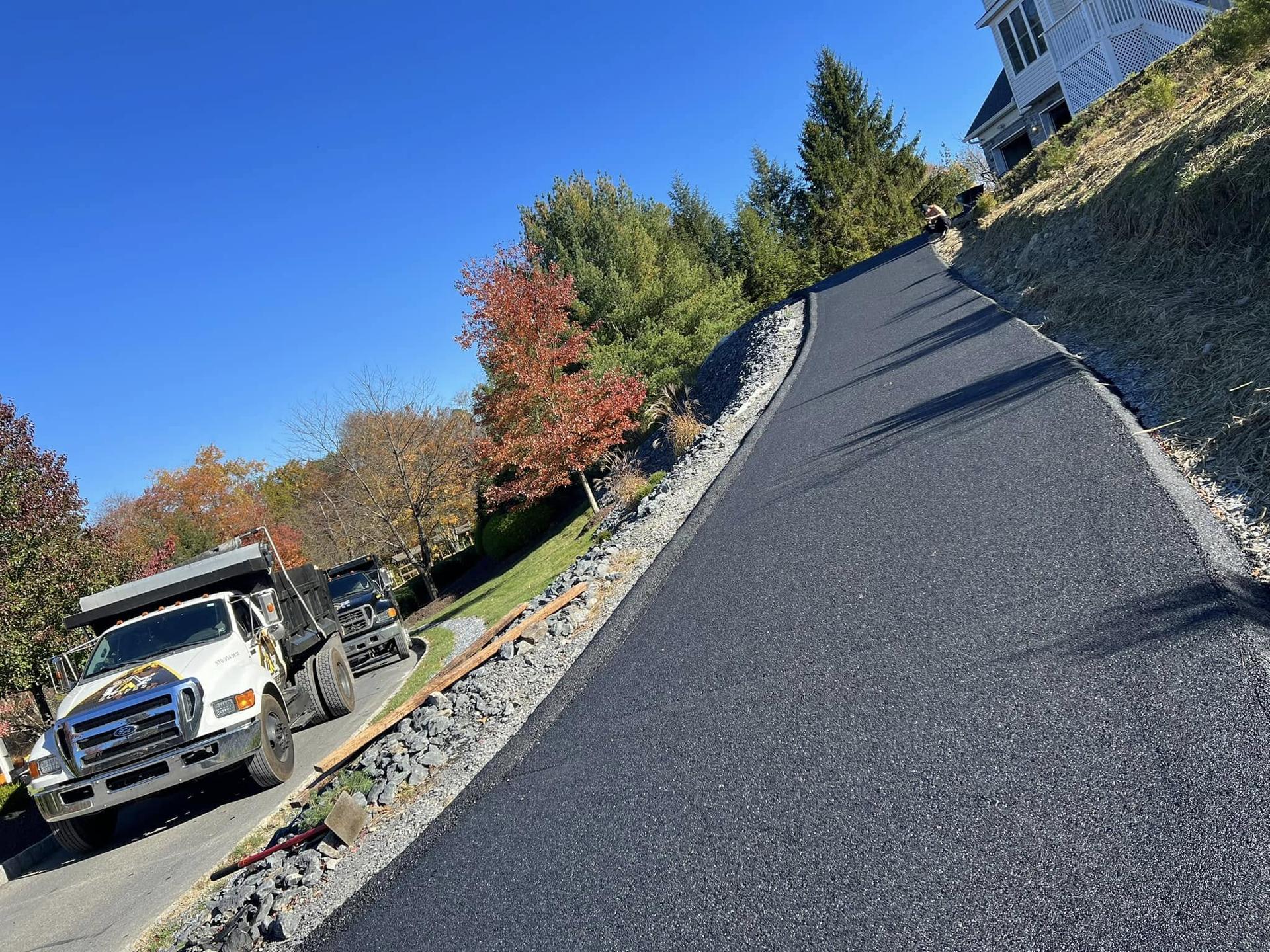 Freshly paved hillside driveway with stone-edge drainage