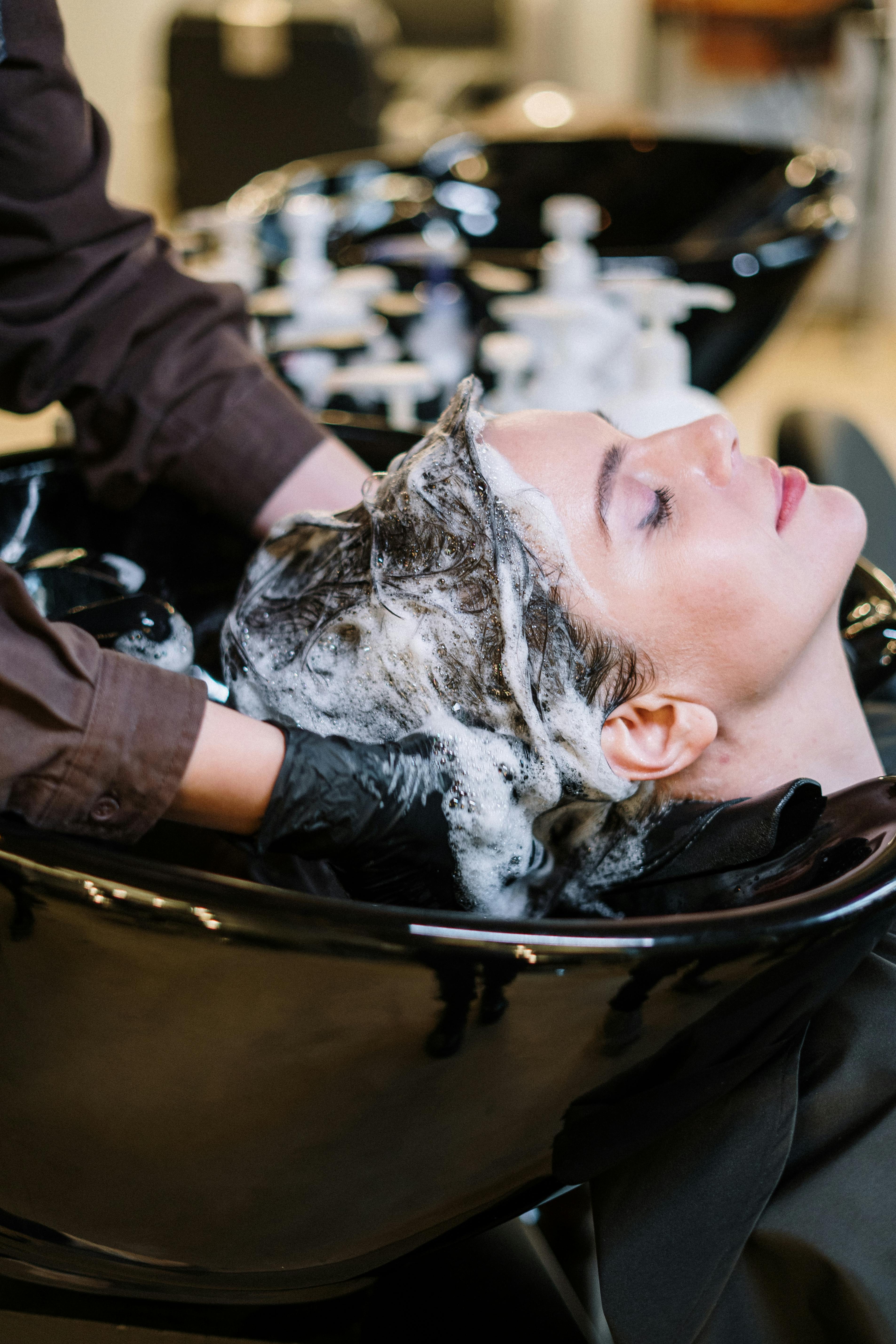 Client receiving a luxurious hair wash at the shampoo bowl by a professional stylist